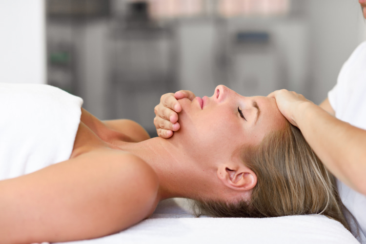 girl lies on the massage table, the chiropractor holds her head