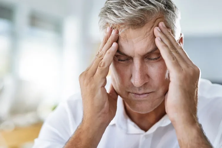 a man is sitting and holding his head